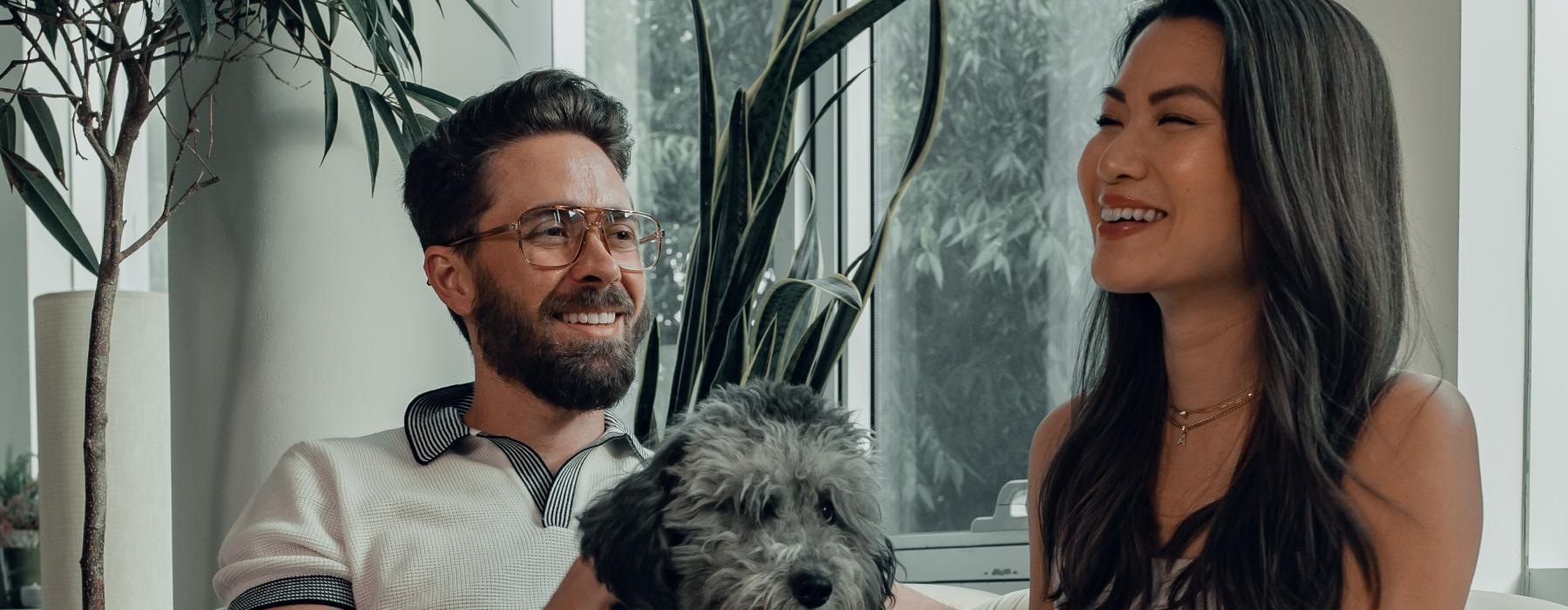 a man and woman sitting on a couch with a dog