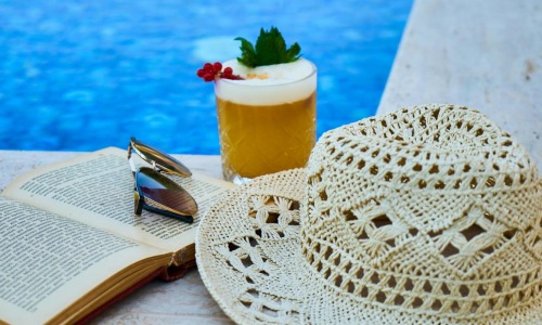 a hat and a book on a pool ledge