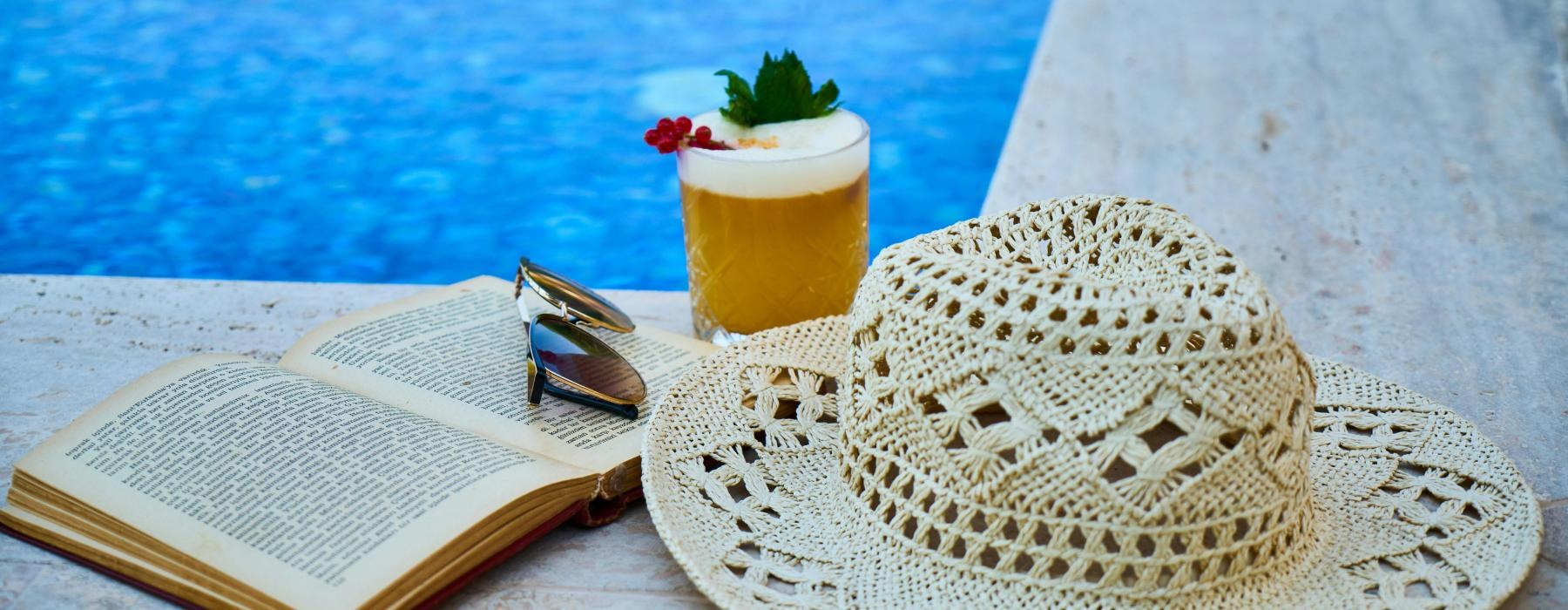 a hat and a book on a pool ledge